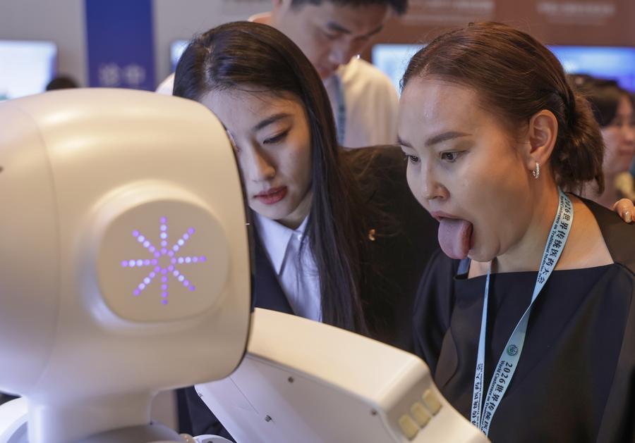 지난 17일 베이징에서 열린 '2026 세계전통의학대회'에서 참가자가 중의학 서비스를 제공하는 체화지능 로봇과 상호작용하고 있다. (사진/신화통신)