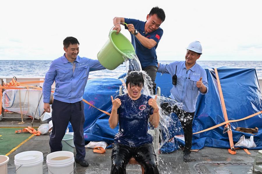 지난달 30일 개인 최고 잠항 기록을 세운 뒤 축하 물세례를 받는 잠수정 조종사 장이(앞). (사진/신화통신)